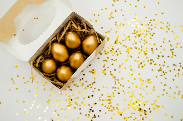 Golden Easter Eggs in a box with golden stars on white background