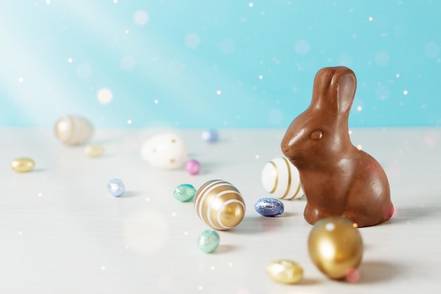 Golden Easter eggs and chocolate Easter bunny over blue background