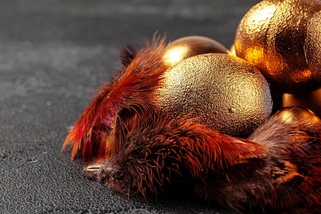 Golden Easter eggs on red bird feathers close up