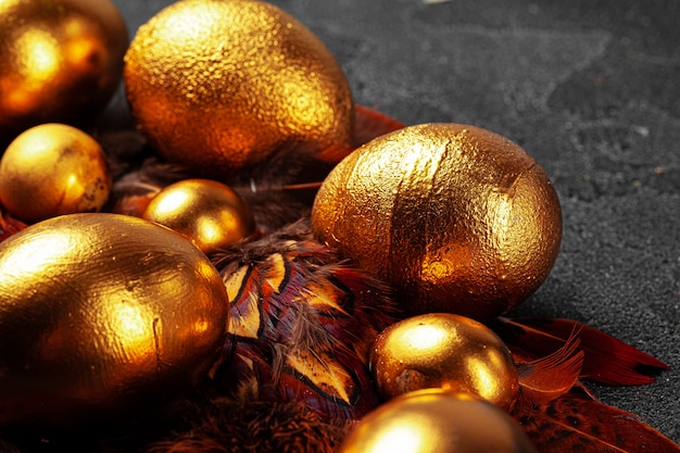 Golden Easter eggs on red bird feathers close up