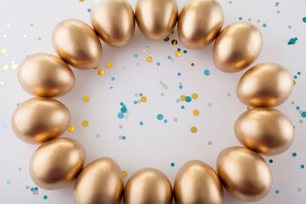 Golden eggs circle  on a white table, sprinkled with sequins