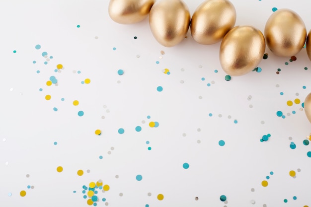 Golden eggs on a white table, sprinkled with sequins