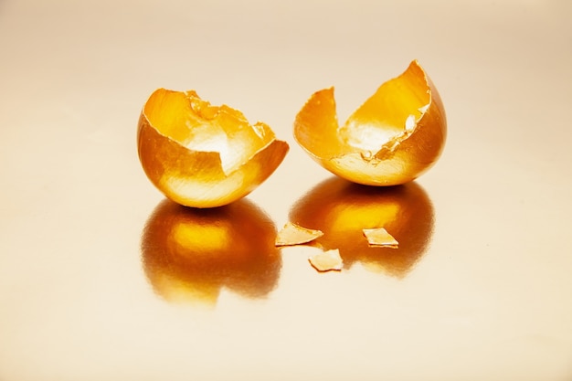 Golden eggshell placed on surface on reflective table