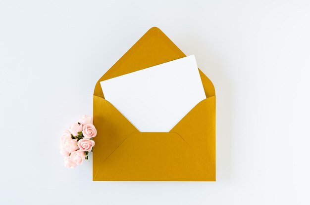 Golden envelope with card and roses on white background