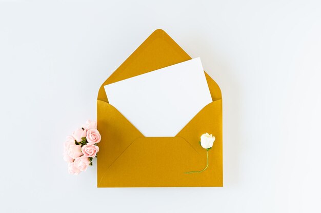 Golden envelope with card and roses on white background