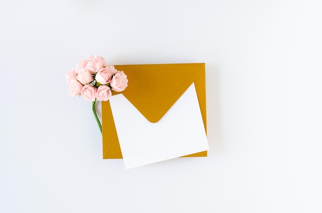 Golden envelope with card and roses on white background