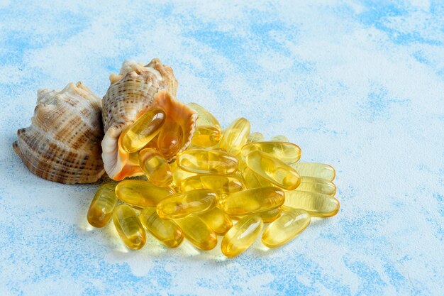 青い背景の上の黄金の魚油カプセル健康と天然の海洋ビタミンの概念