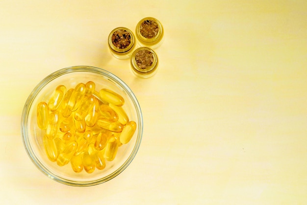 Golden fish oil capsules on a yellow background the concept of health and natural marine vitamins