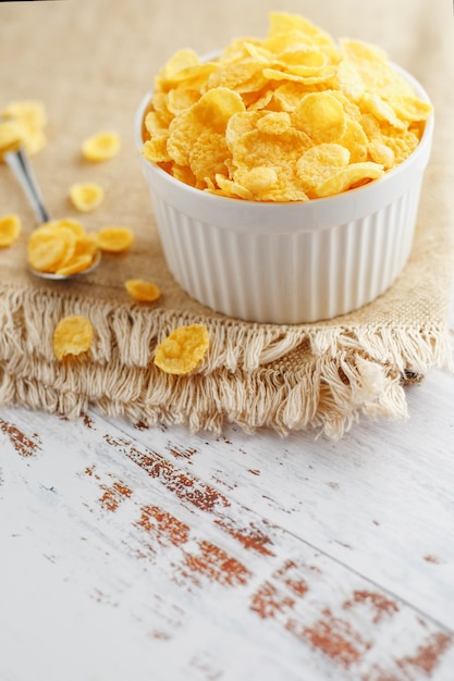 Golden flakes in a cup on burlap, on a light wooden table