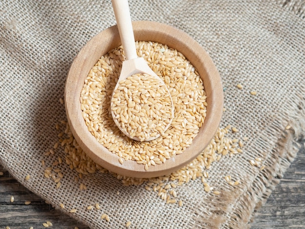 Golden flax seeds, flaxseed in a wooden spoon on an old rustic background close-up, white flax