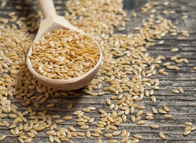 Photo golden flax seeds, flaxseed in a wooden spoon on an old rustic background close-up, white flax