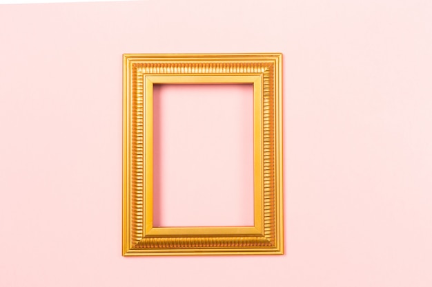 Golden frame empty blank picture on light pink background .