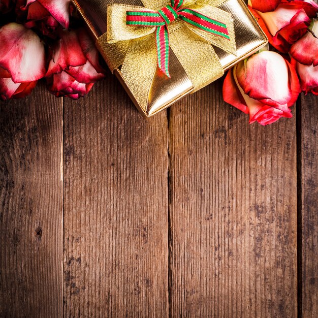 Confezione regalo dorata e bouquet di rose sul tavolo