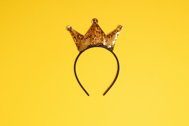 Photo golden glitter crown headband on yellow background.