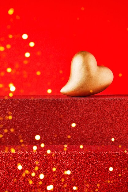 Foto cuore d'oro su un podio rosso brillante con copia spazio. concetto di celebrazione di san valentino