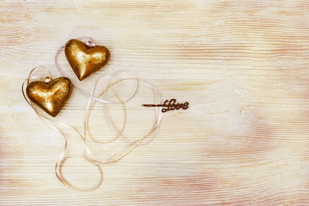 Golden hearts with ribbon on old wood