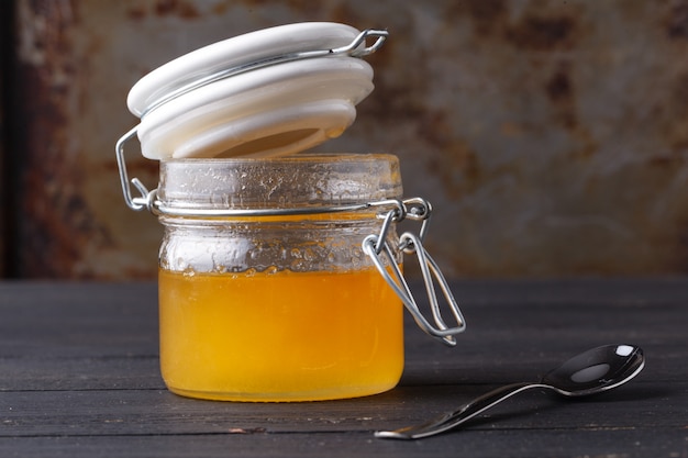 Golden honey in glass jar on rustic table