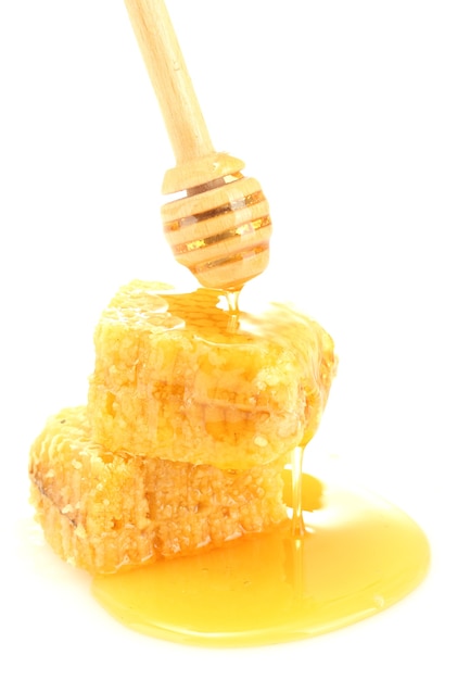 Golden honeycombs and wooden drizzler with honey on white