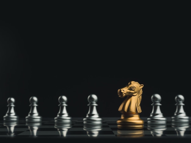 The golden horse, knight chess piece standing in front of silver pawn chess pieces on chessboard on dark background. Leadership, follower, team, commander, competition, and business strategy concept.