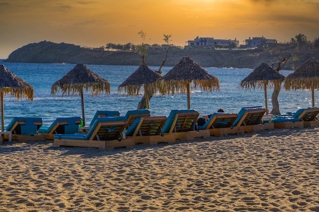 Golden hour luxurious beach chairs umbrellas by empty sandy beach at Mykonos Greece