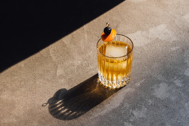 Golden hour whiskey soda highball cocktail with ice cherry orange peel garnish