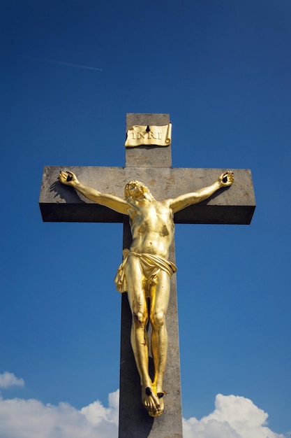 Foto golden jesus christ crocifissione statua soleggiata giornata estiva cielo blu sullo sfondo vrbice moravia repubblica ceca