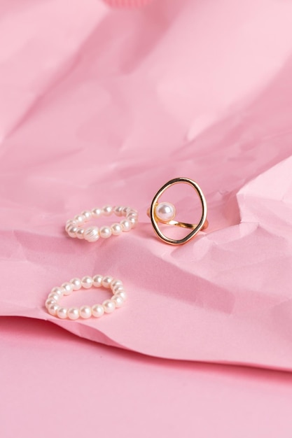 Golden jewelry on a pink background Stylish gold ring with pearl on pink background Product photo