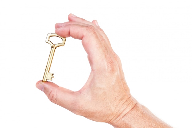Фото Золотой ключ в руке символ богатого дома. на белой стене.