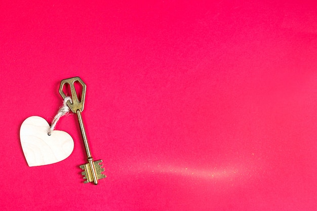 Foto chiave d'oro con etichetta in legno a forma di cuore su fondo rosso. san valentino, dichiarazione d'amore, copia dello spazio. sentimenti aperti e chiusi. dolce casa, immobiliare