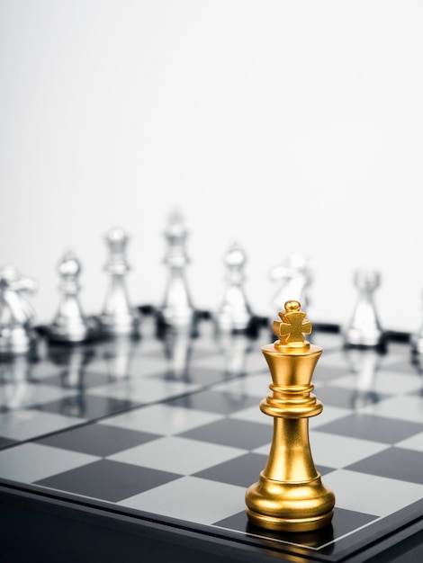 The Golden king chess piece standing on chessboard corner in front of silver chess pieces on white background vertical Leadership fighter competition confrontation and business strategy concept