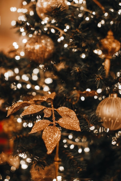 Golden leaves and christmas ball hanging on the christmas tree\
magic bokeh lights festive garlands