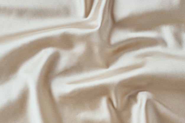 Фото Золотой легкий шелк со складками. абстрактная текстура рифленой атласной поверхности