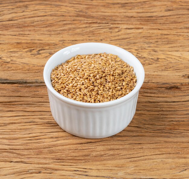 Golden linseed on a bowl over wooden table.