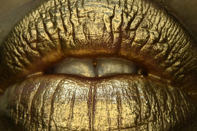 Golden lips macro close up Luxury gold lips makeup Golden lips with golden lipstick Gold paint on lips of sexy girl Sensual woman mouth isolated background