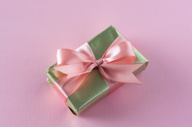 Golden luxury gift box over pink surface, 