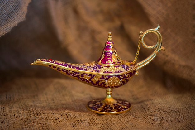 Golden magic genie lamp on burlap, close up. lamp of desires from the story of Aladdin with Genie