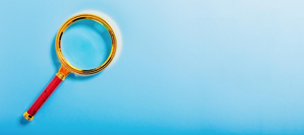 Golden magnifier on blue paper background