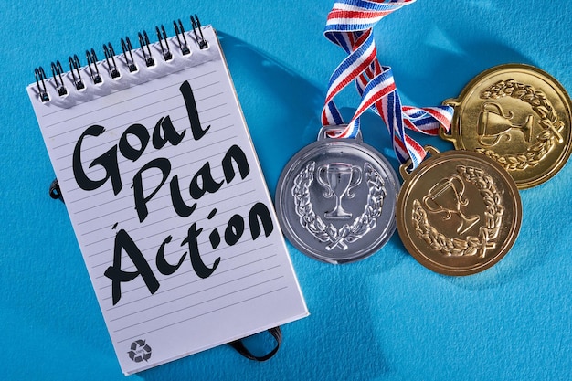 Golden medal with written text goal plan action on blue background