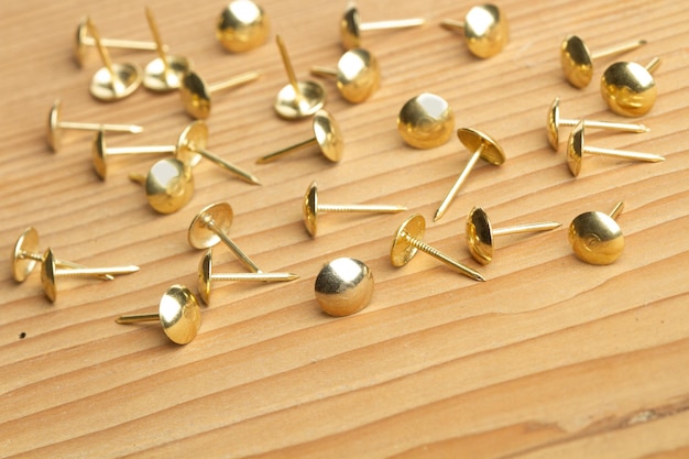 Photo golden metal tintacks on a wooden table with copy space