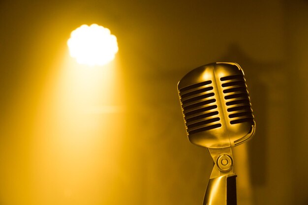 Golden microphone on the yellow dim light background and space for content