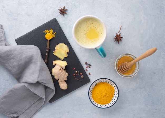 golden milk with turmeric, spice and honey on blue  background