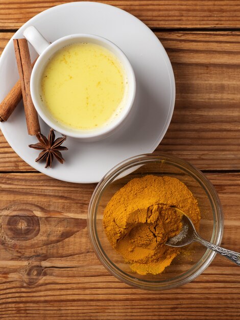 Golden milk with turmeric on wooden table