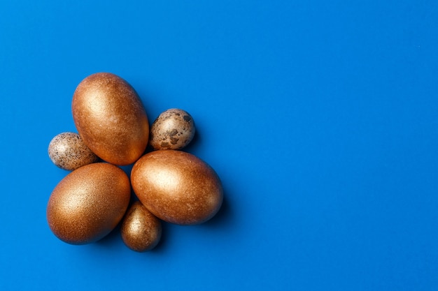 Золотые современные пасхальные яйца, изолированные на синем