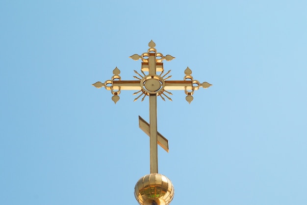 Golden orthodox cross with blue sky background