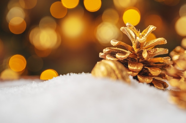 雪のテーブルのクリスマスの装飾に金色に塗られた松ぼっくり