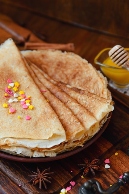 Golden pancakes with frozen fruits, decor and honey in a rustic style