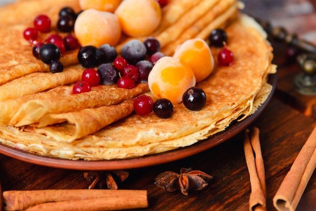 Golden pancakes with frozen fruits, decor and honey in a rustic style