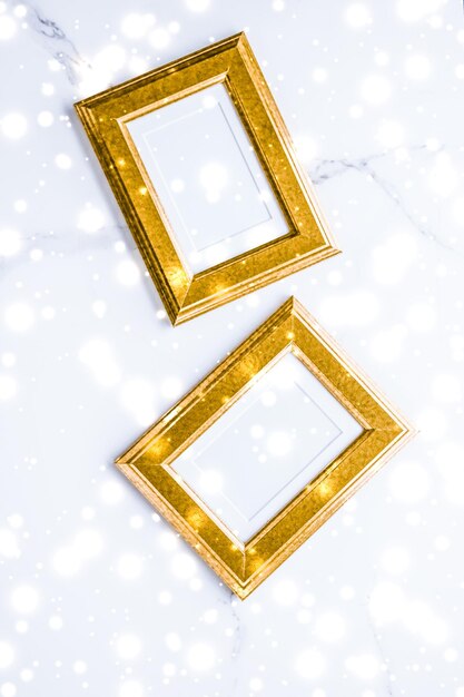 Photo golden photo frame and glowing glitter snow on marble flatlay background for christmas and winter holidays