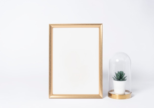 Golden photo frame mock up and plants in vase Interior decor home elements.