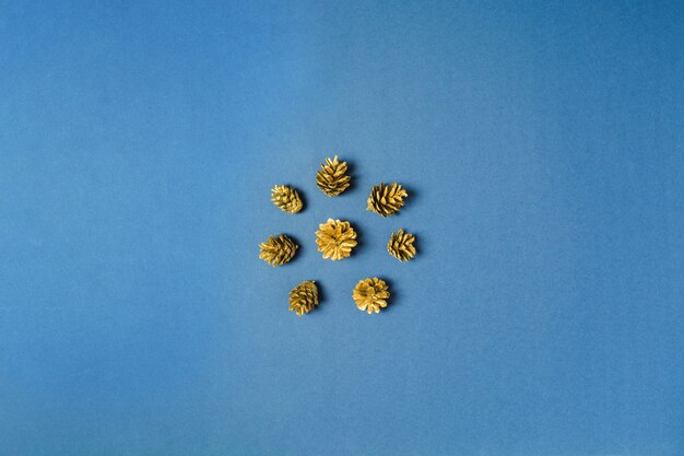 Golden pine cones in circle in center on blue background